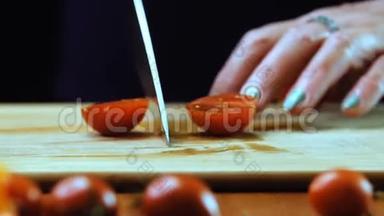 一个女人正在用菜刀切一个樱桃番茄。